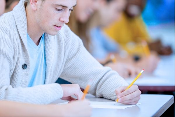 Persona joven escribiendo en clase durante un examen, relacionada con opositar TIC en 7 días