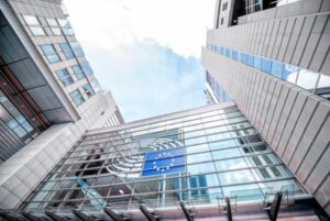 Fachada del Parlamento Europeo con la bandera de la UE, símbolo institucional relacionado con la Oficina Europea de IA