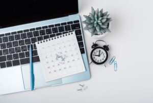 Calendario y portátil sobre escritorio, símbolo de la actualización del cronograma del Cuerpo Superior de Sistemas del Estado.