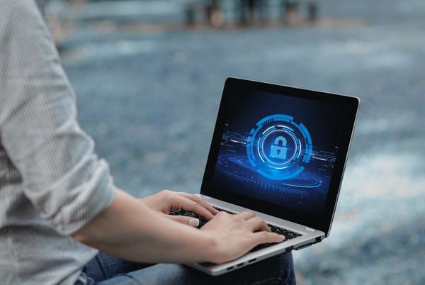 Persona utilizando un ordenador portátil con un icono de seguridad digital, relacionado con la ciberseguridad sanitaria.