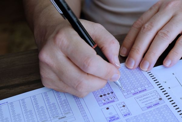 Mano rellenando una hoja tipo test en un examen, relacionada con el examen de inglés del CSSTIAE 2025.