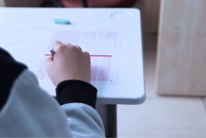 Persona realizando un examen tipo test en un aula, relacionado con los aprobados del tercer ejercicio CSSTIAE.