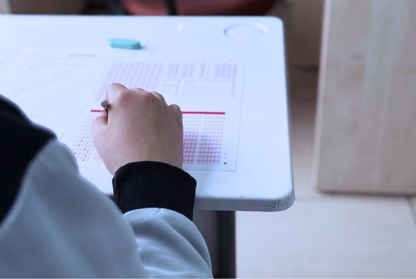 Persona realizando un examen tipo test en un aula, relacionado con los aprobados del tercer ejercicio CSSTIAE.