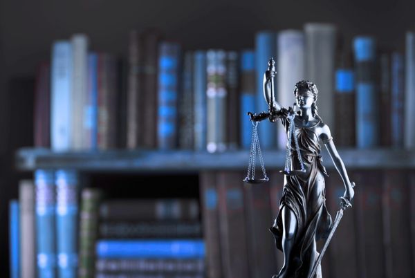 Estudio de la legislación para oposiciones TIC representado por una figura de la justicia ante libros jurídicos.