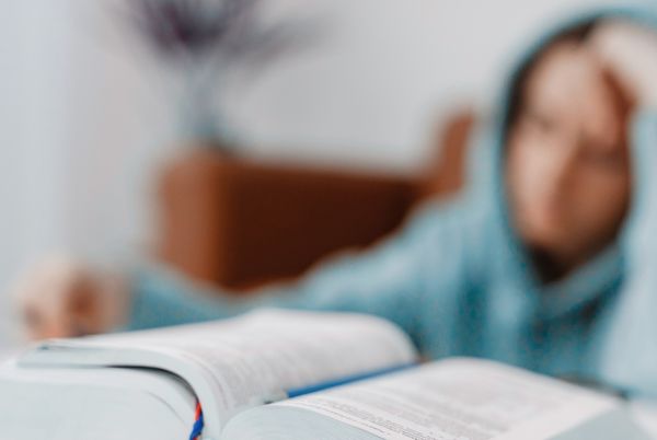 Opositor TIC estudiando con gesto de cansancio y libro abierto sobre la mesa