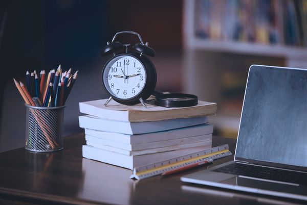 Opositor estudiando con reloj y libros sobre la mesa, concepto de gestión del tiempo y productividad en oposiciones.