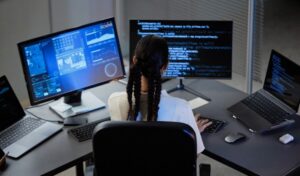 Profesional IT estudiando oposiciones TIC frente a varios monitores con código