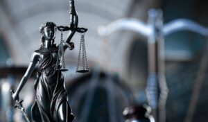 Estatua de la Justicia con balanza en primer plano, representando la digitalización de los servicios judiciales