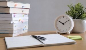 Mesa de estudio con apuntes, libros y reloj representando la planificación y el repaso en oposiciones TIC.